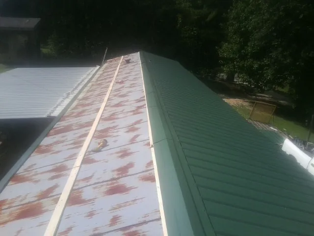 Old rusted panels beside newly installed green metal roofing — Wind Damage Roof Repair by Roofing Brothers in Charleston