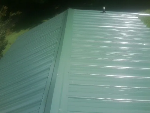 New green metal panels meeting at the ridge of a roof — Flat Roof Repair work by our crew in Charleston